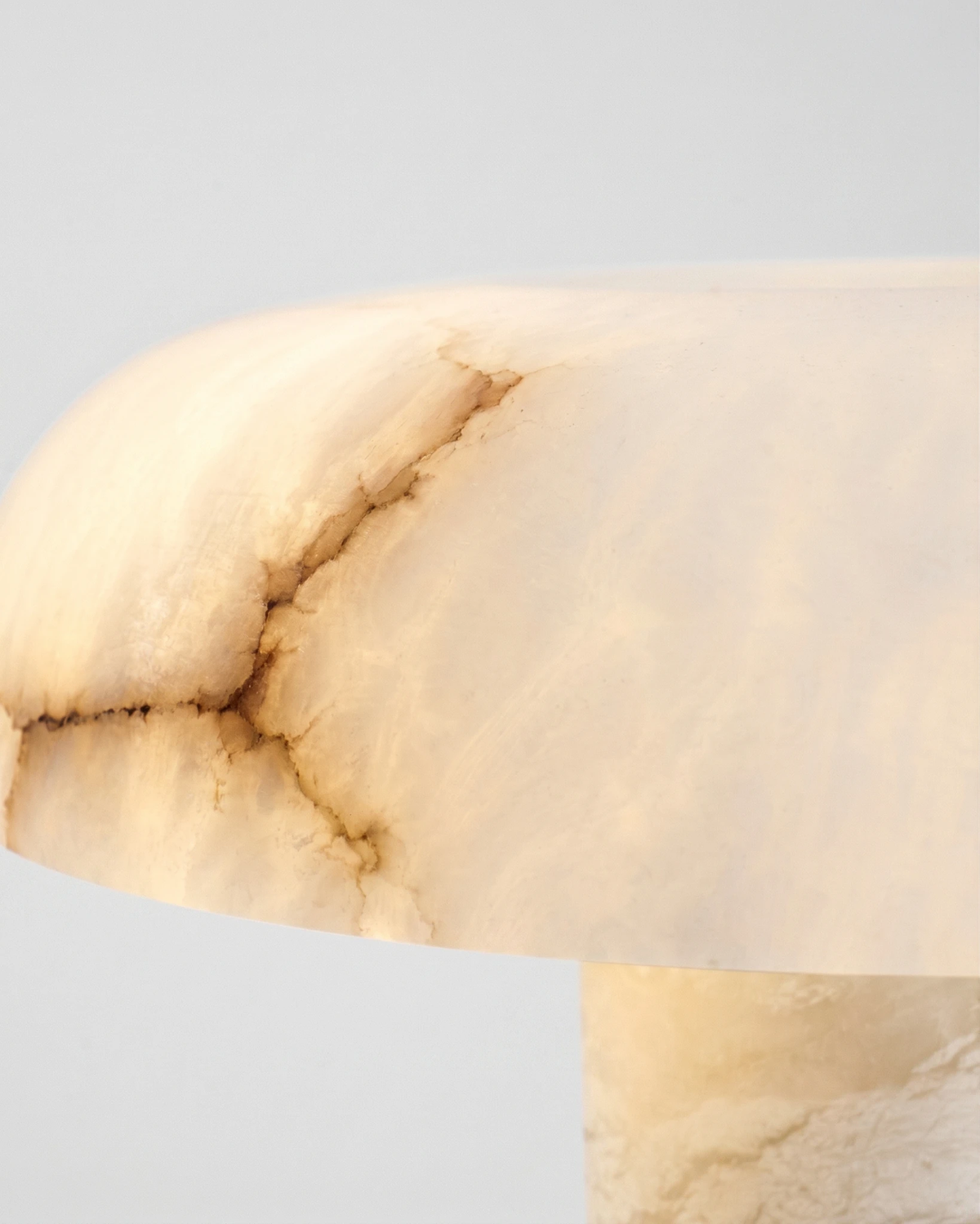 Close-up of the veined alabaster dome edge of the alabaster table lamp OBSI No.01, lit from within