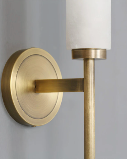 Close-up of the brushed brass backplate and arm of the ALABA No.01 alabaster wall sconce