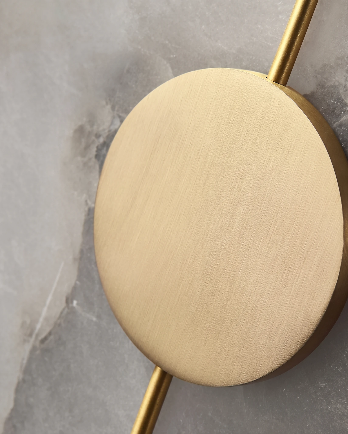 Close-up of the brushed brass disc and inlay line on the gray alabaster of the OLIVA No.03 wall sconce, unlit