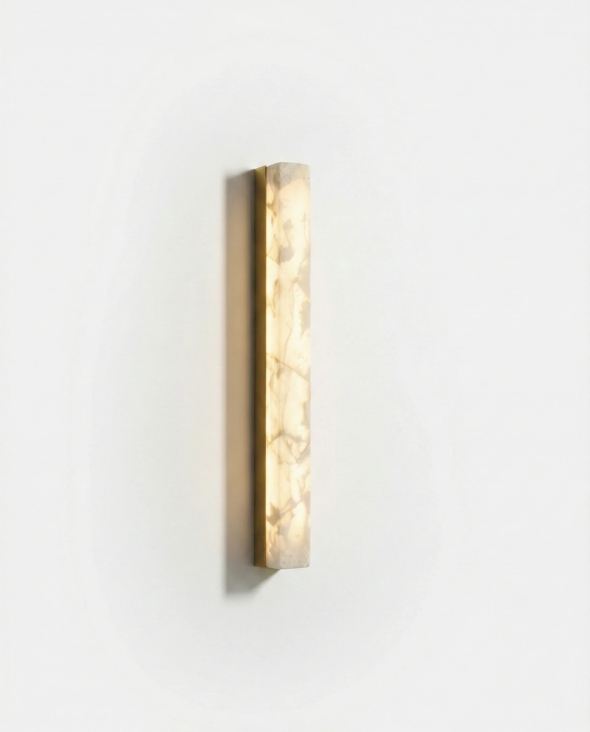 Alabaster wall sconce NEBBIA No.02 in the 24 in size on a brass bar, switched on, front view on a white wall