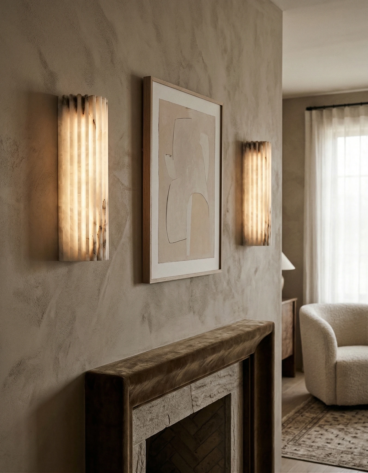 Two alabaster wall sconces ALABA No.02 lit on either side of a framed print above a stone fireplace mantel