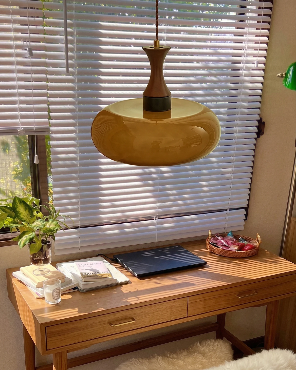Amber glass pendant light OVIA No.04, disc shade hanging over a wooden desk by a window with blinds