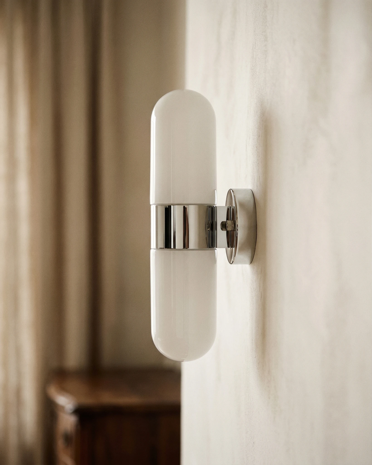 Close-up of the polished chrome band joining the two opal capsules of the COMETA No.01 brass wall sconce, unlit