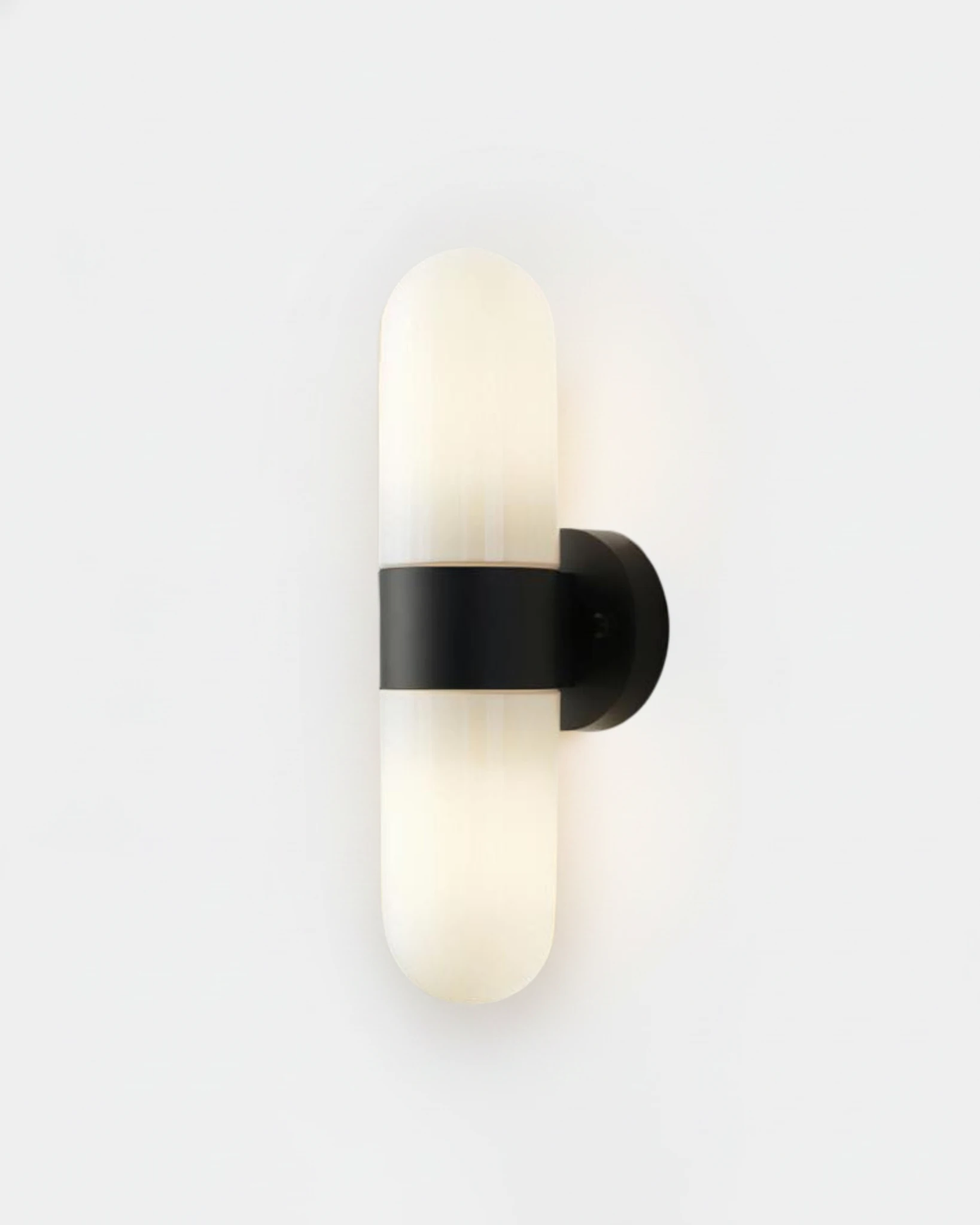 Brass wall sconce COMETA No.01 in Matte Black, two glowing opal capsules joined by a black band