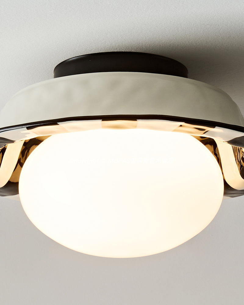 Close-up of the OLEA No.02 ceramic flush mount ceiling light from the side, globe lit under the white corolla