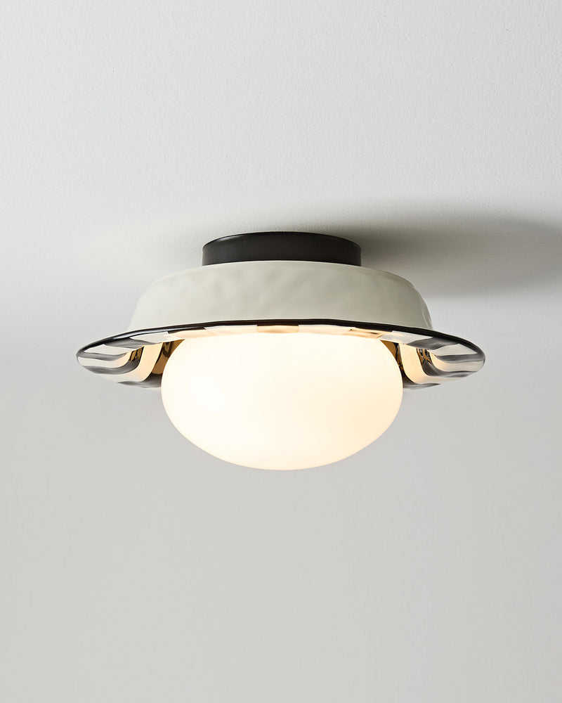 Ceramic flush mount ceiling light OLEA No.02 seen from an angle with the opal globe switched on