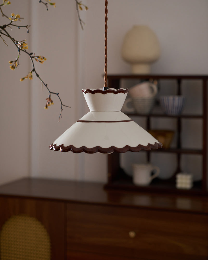 Ceramic pendant light MELI No.04 hanging above a wooden sideboard with shelves of cups and ceramics