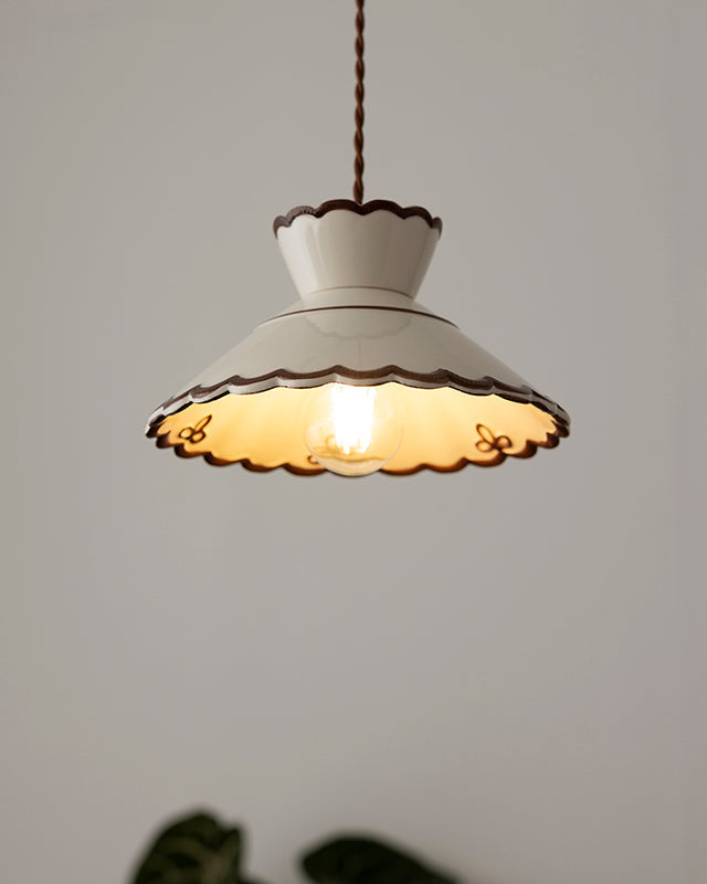 Ceramic pendant light MELI No.04 switched on, scalloped cream shade with brown edge and foliage below