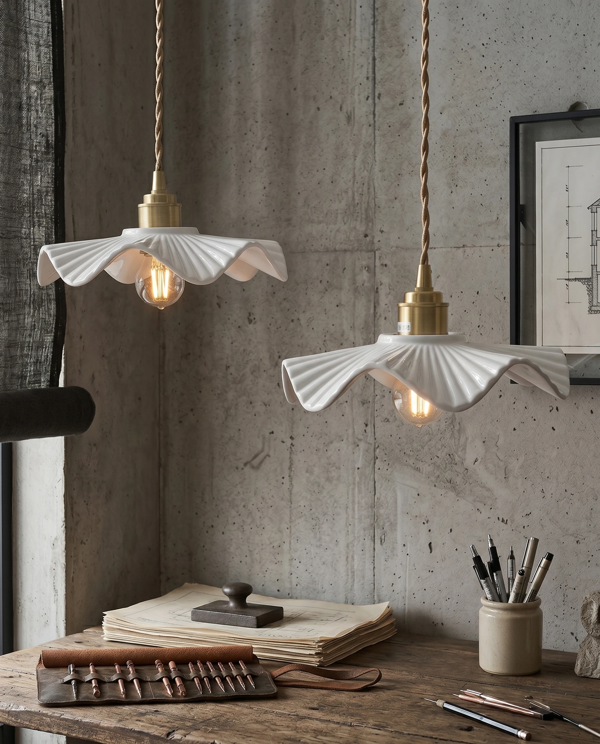 Ceramic pendant light ALBA No.01, two wavy shades lit above a workbench with brushes and tools by a concrete wall