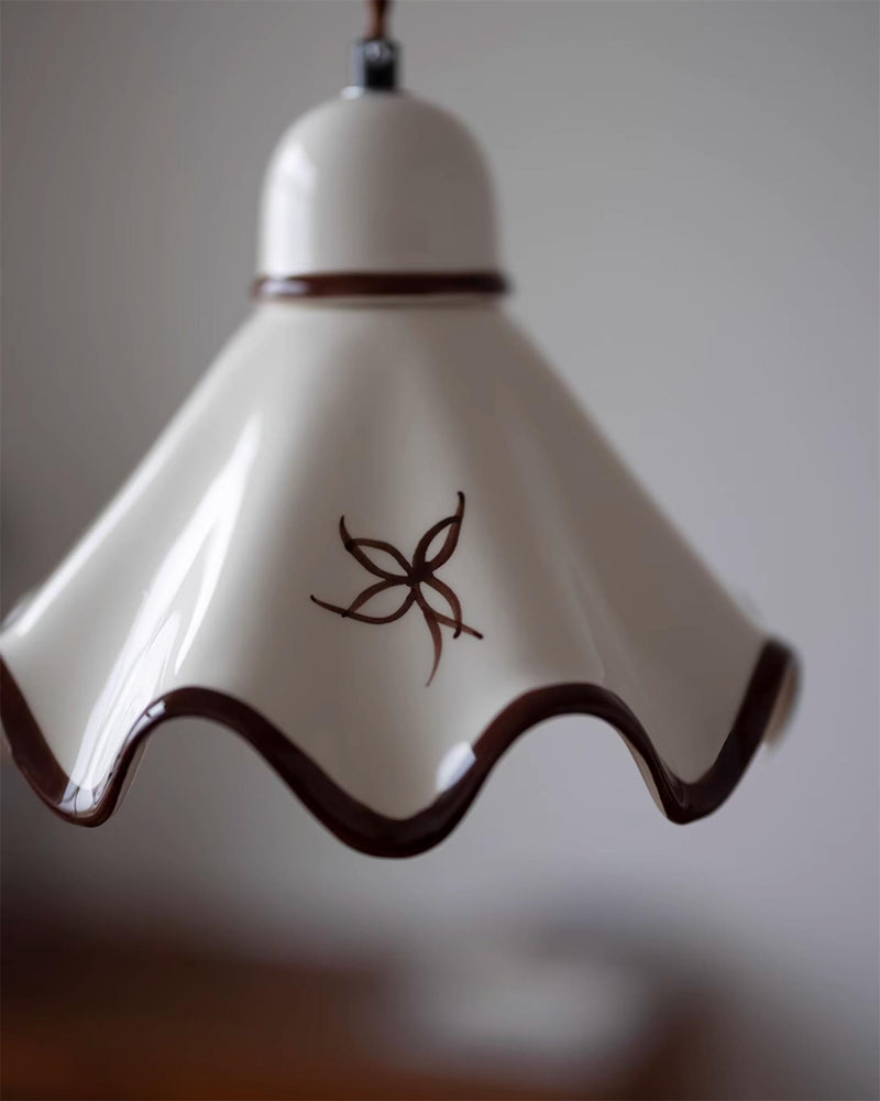 Close-up of the CAPRI No.01 ceramic pendant light showing the glossy white glaze, brown scalloped edge and a painted flower