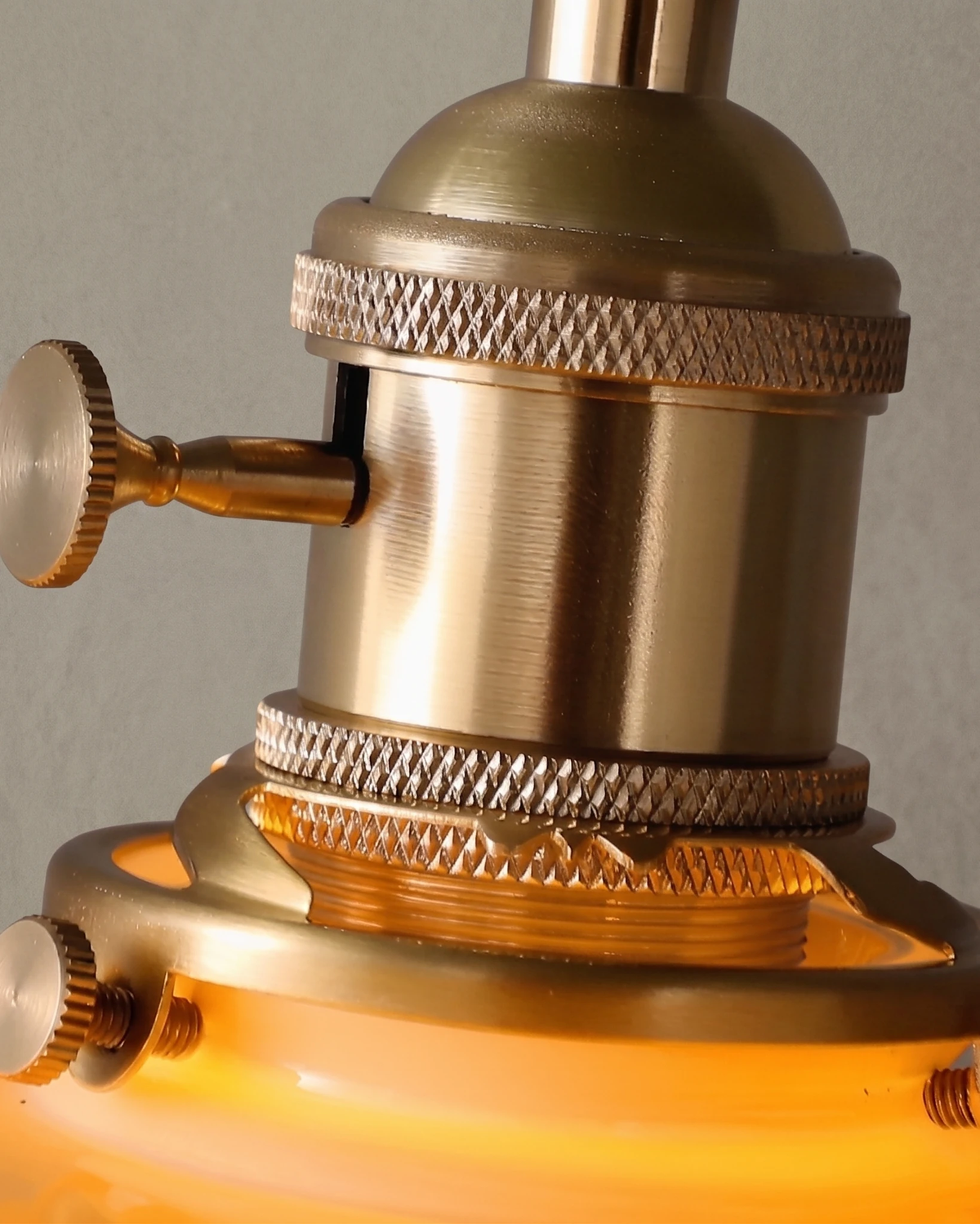 Close-up of the knurled brass socket and switch of the ceramic pendant light CORA No.01 with the shade lit