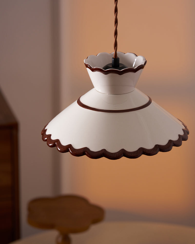 Close-up of the scalloped brown-trimmed rim of the ceramic pendant light MELI No.04 in warm light