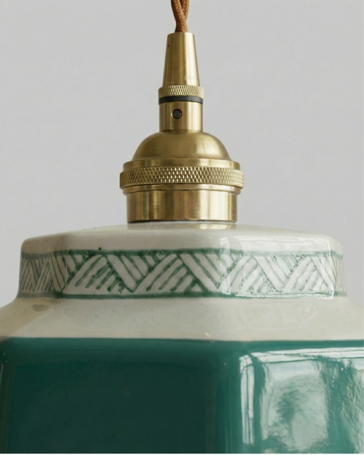 Close-up of the RAGUSA No.01 ceramic pendant light in forest green, brass socket above the patterned band