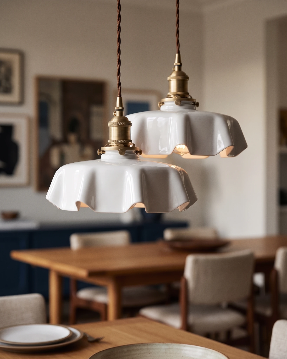 Ceramic pendant light CORA No.01 in bone white lit above a wooden dining table with plates, blue kitchen behind