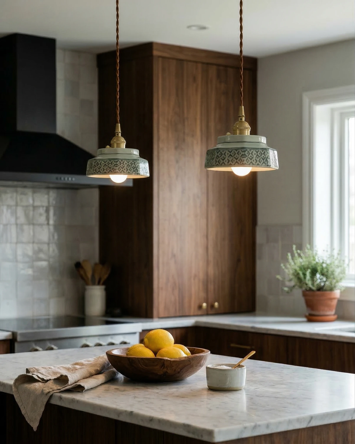 Two ceramic pendant lights RAGUSA No.02 switched on over a marble kitchen island with a bowl of lemons