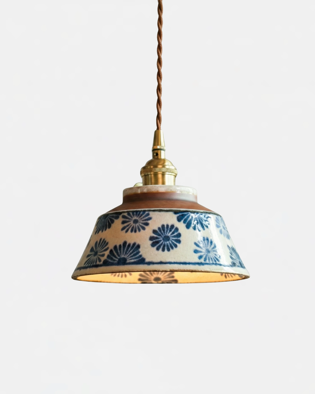 Ceramic pendant light MELI No.05 in Indigo Floral, blue flowers on a white bell with brass fitting and twisted cord, lit