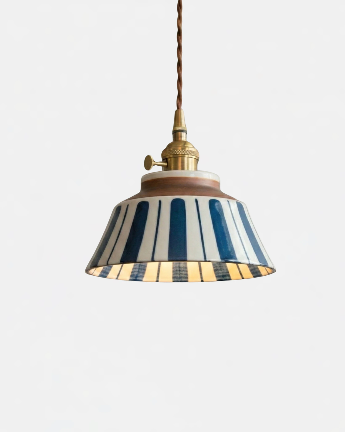 Ceramic pendant light MELI No.05 in Mariner Stripe, bold blue vertical stripes on a white bell, switched on