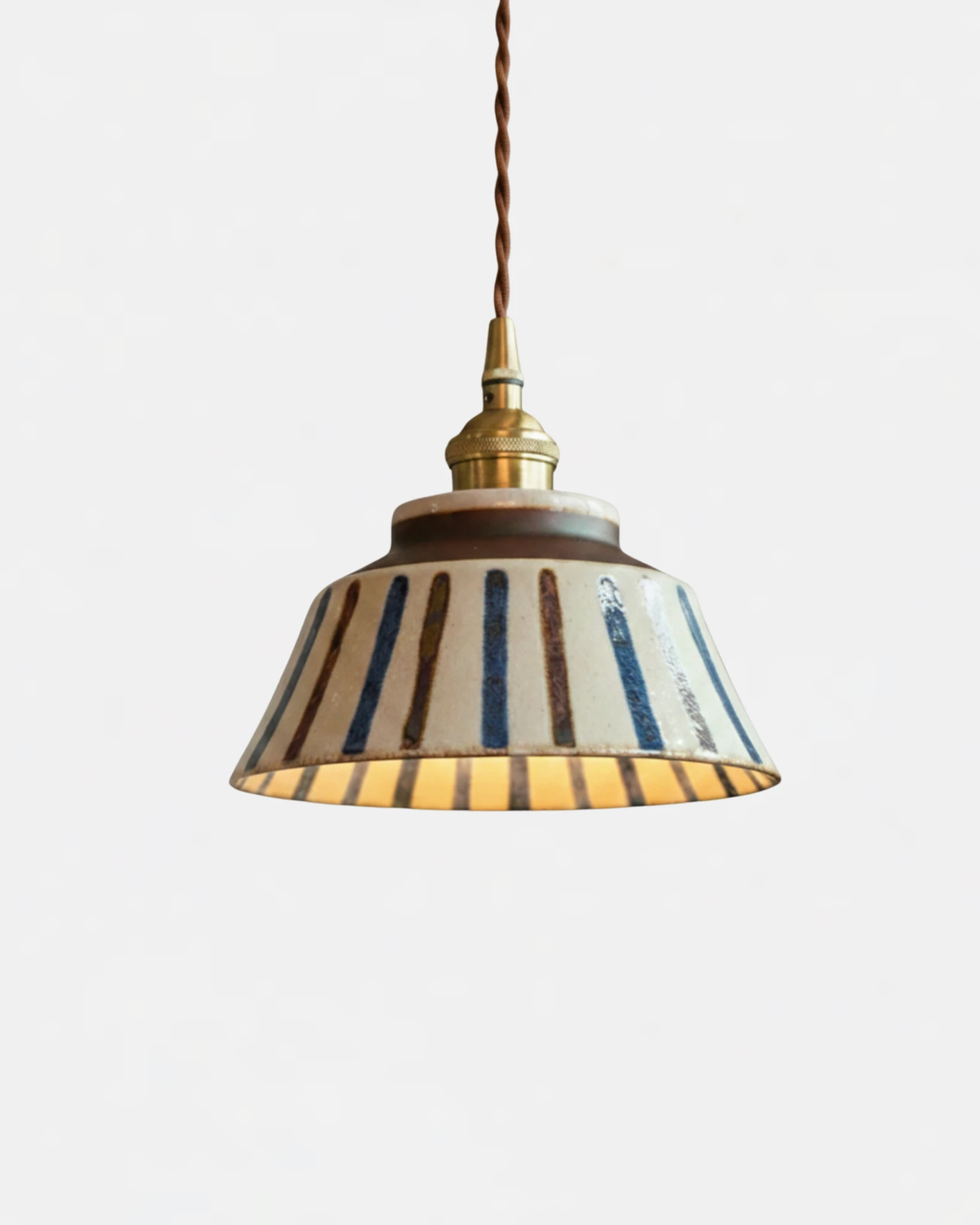 Ceramic pendant light MELI No.05 in Ribbed Earth, thin brown and blue stripes on a cream bell, switched on