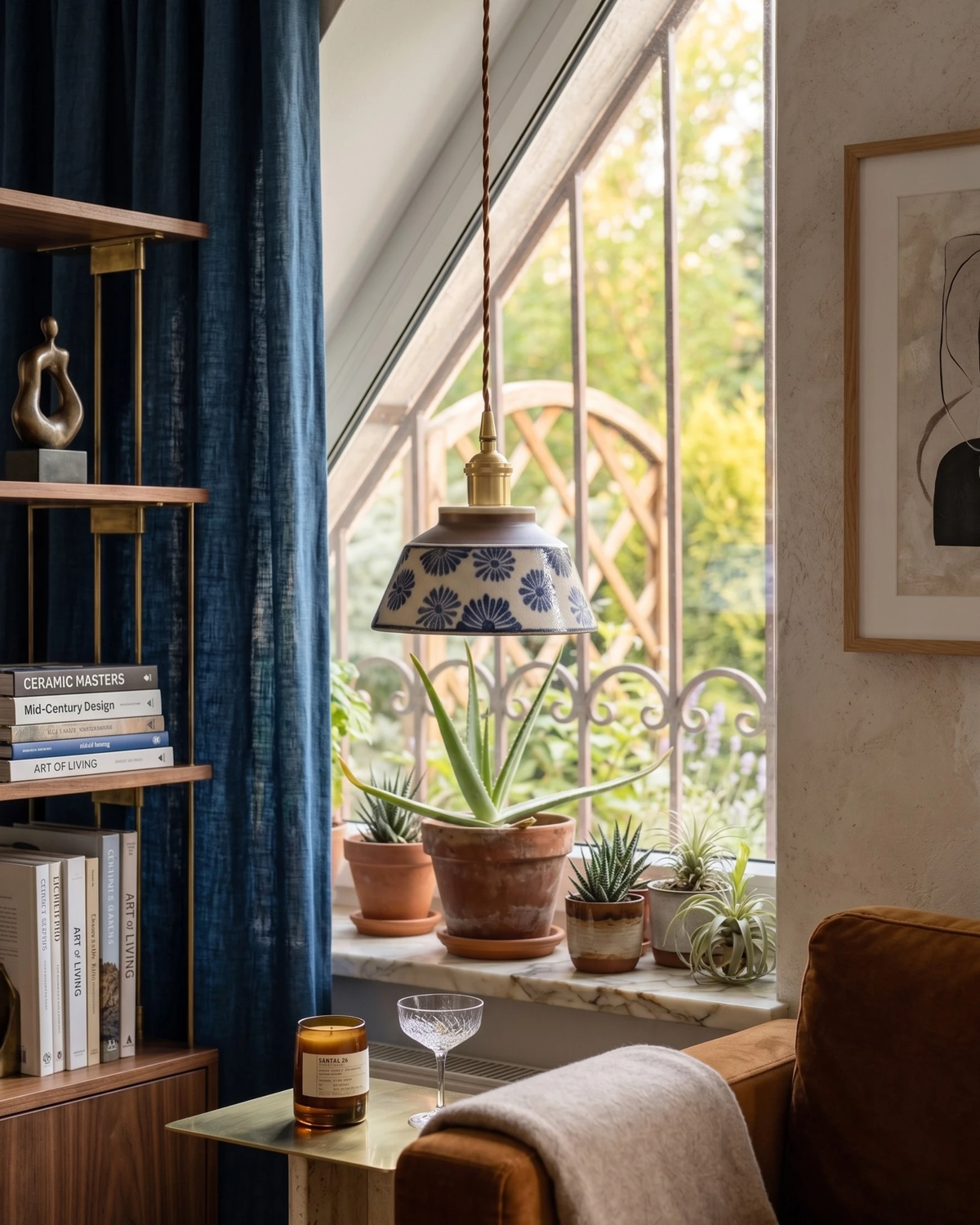 Ceramic pendant light MELI No.05 in indigo floral hanging by a window with potted plants and a blue curtain