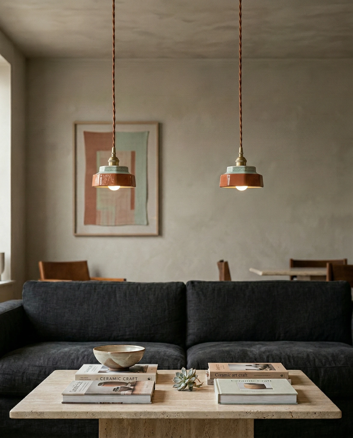 Two ceramic pendant lights RAGUSA No.01 in oxblood red lit above a travertine coffee table and a dark sofa