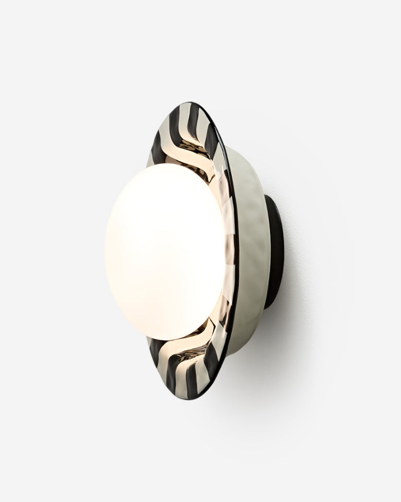 Ceramic wall sconce OLEA No.01 in Black and White, striped ceramic corolla around a glowing opal globe, angled view