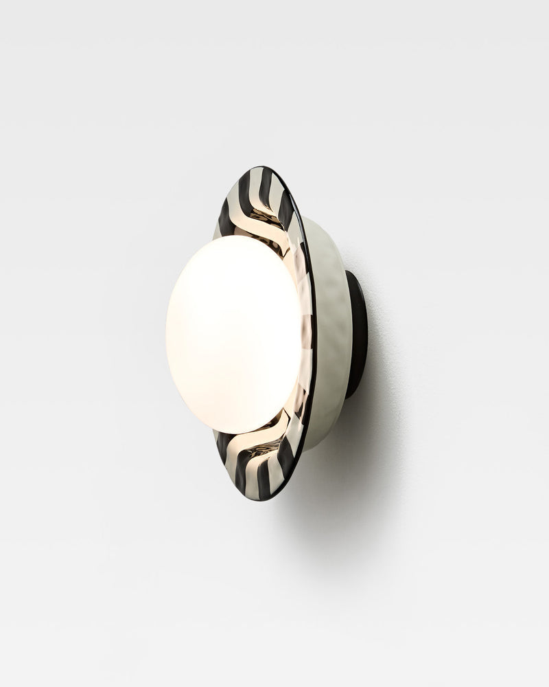 Ceramic wall sconce OLEA No.01 in Black and White, three-quarter view of the striped rim and glowing globe