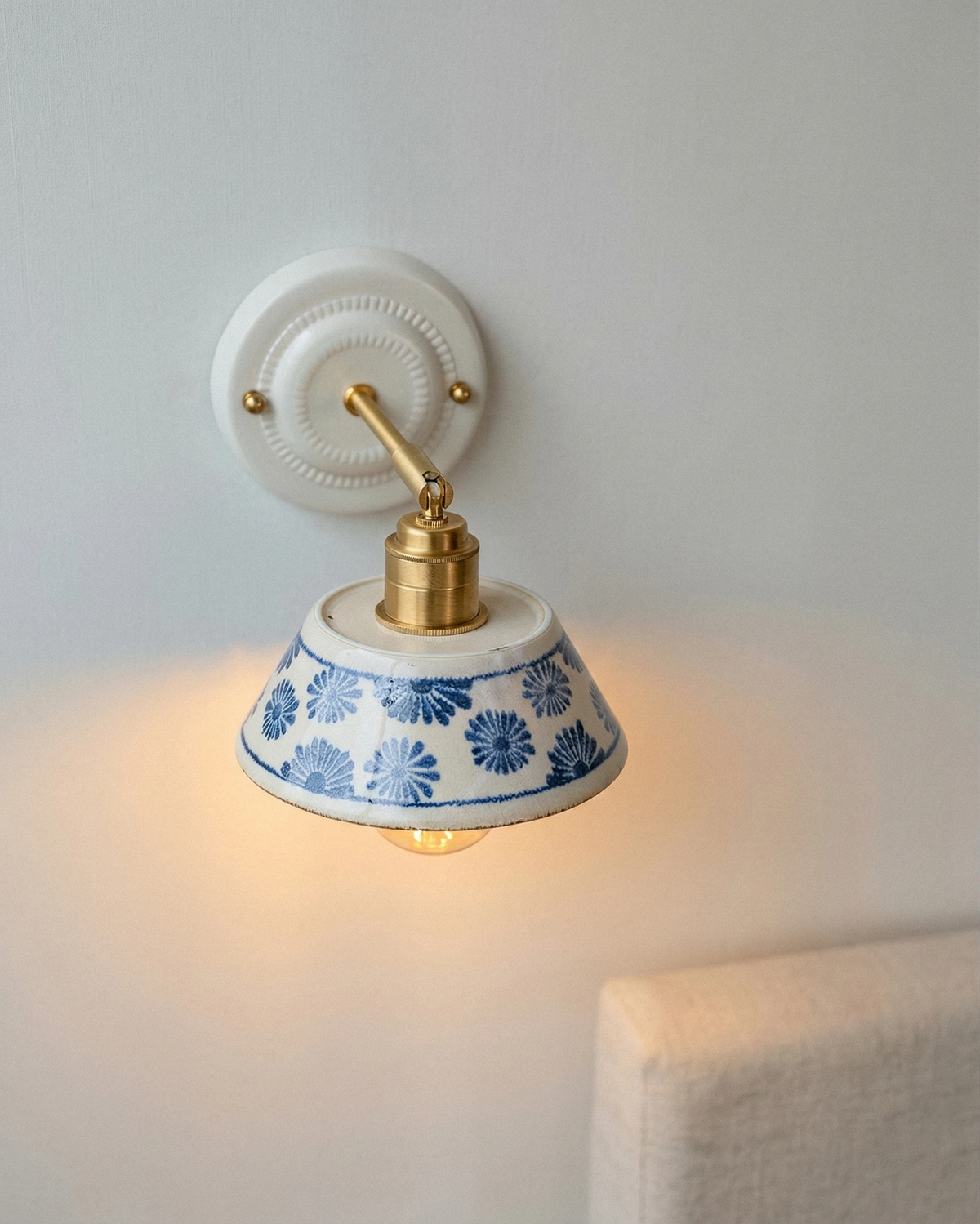 Ceramic wall sconce FIORA No.01 switched on, blue floral ceramic shade glowing
