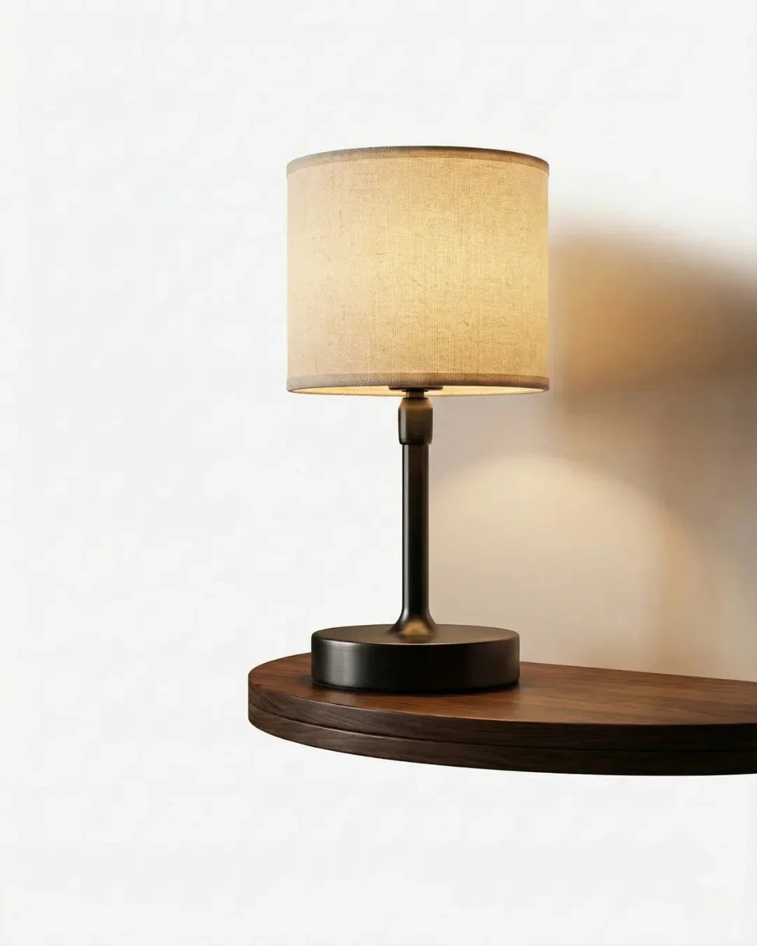 Cordless bedside lamp BOLOGNA No.01 in Matte Black with Natural Linen, drum shade glowing on a slim black stem and base