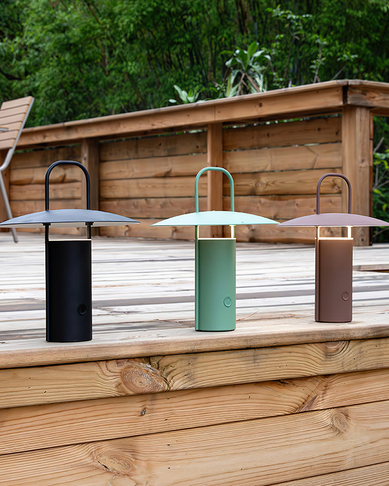 Three cordless lantern lamps PORTO No.01 in black, green and brown standing on a wooden deck step