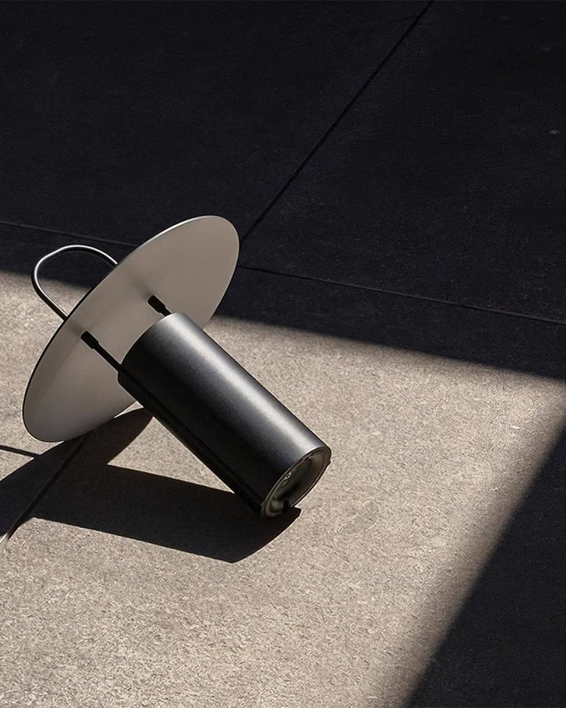 Cordless lantern lamp PORTO No.01 in black lying on its side on a concrete floor in sunlight, unlit