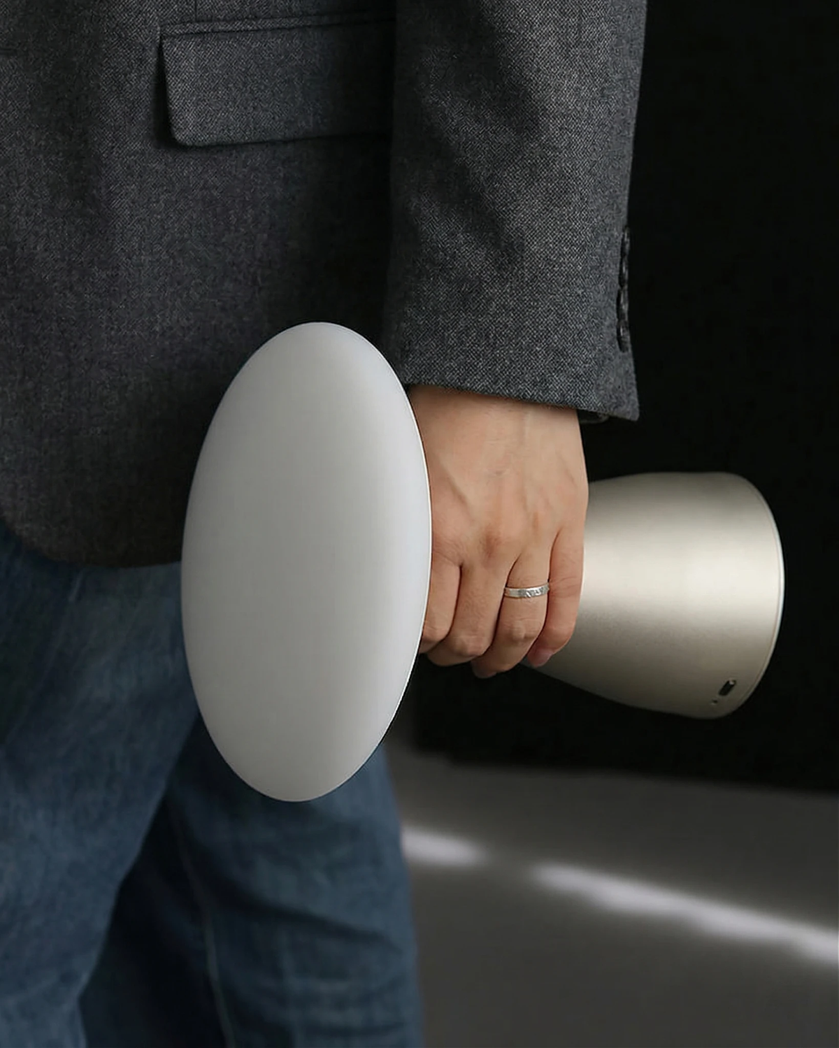 Cordless mushroom lamp DOMA No.03 unlit, tucked under the arm of a person in a gray blazer and jeans