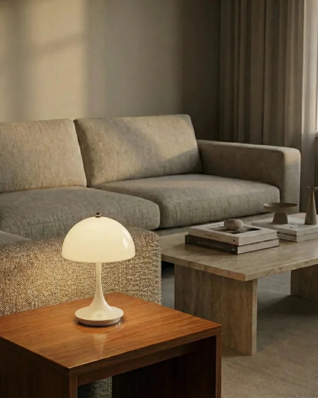 Cordless mushroom lamp FONTE No.01 in soft white glowing on a wooden side table beside a linen sofa