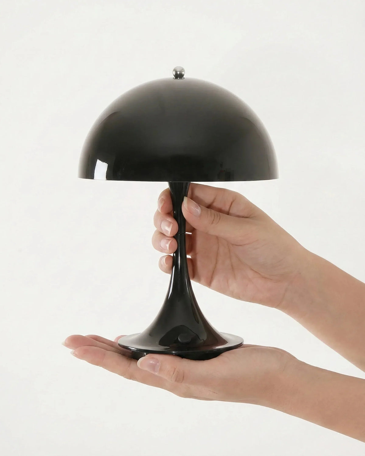 Cordless mushroom lamp FONTE No.01 in volcano black held in an open hand to show its compact size