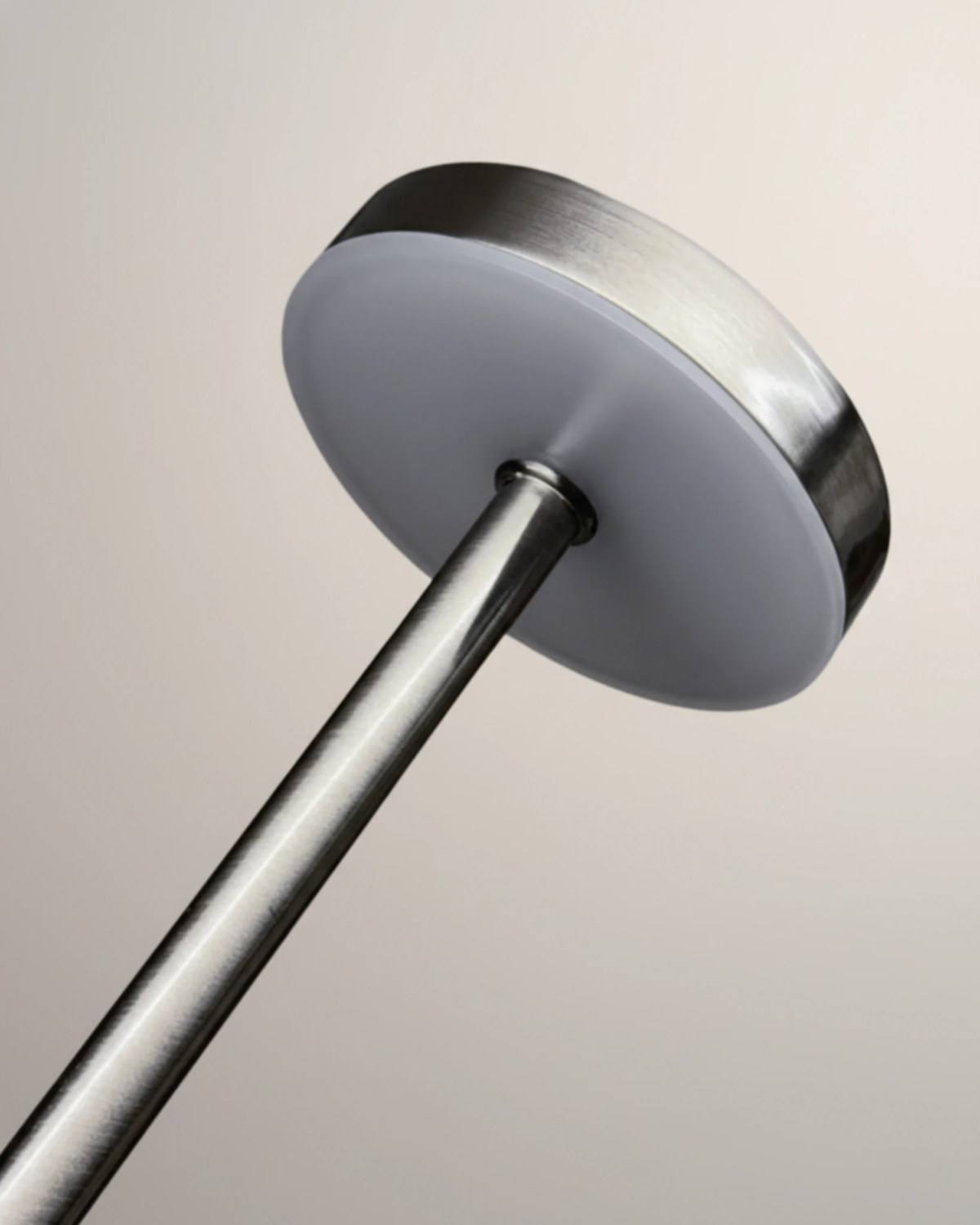 Close-up of the brushed silver disc head of the RIETI No.01 cordless table lamp seen from below