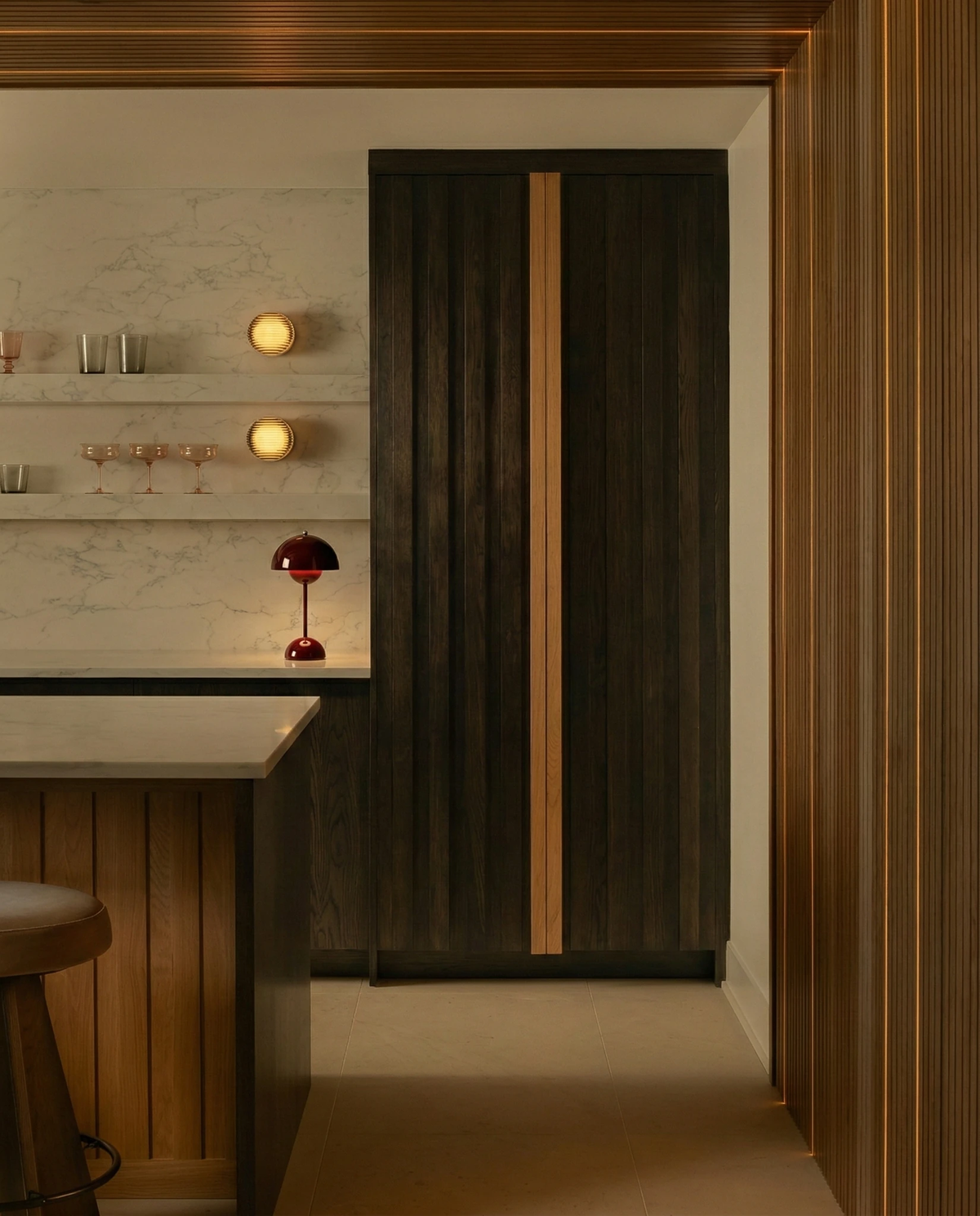 Cordless table lamp DOMA No.02 in wine red switched on at a kitchen counter with marble backsplash and wood cabinetry