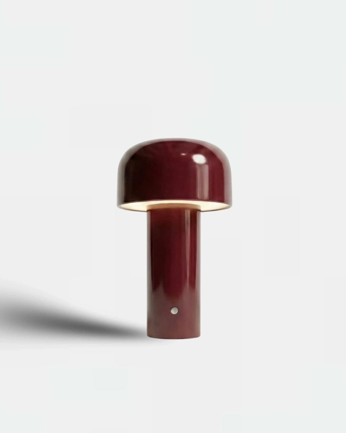 Cordless table lamp DOLCE No.01 in bordeaux red with the domed head switched on, plain background