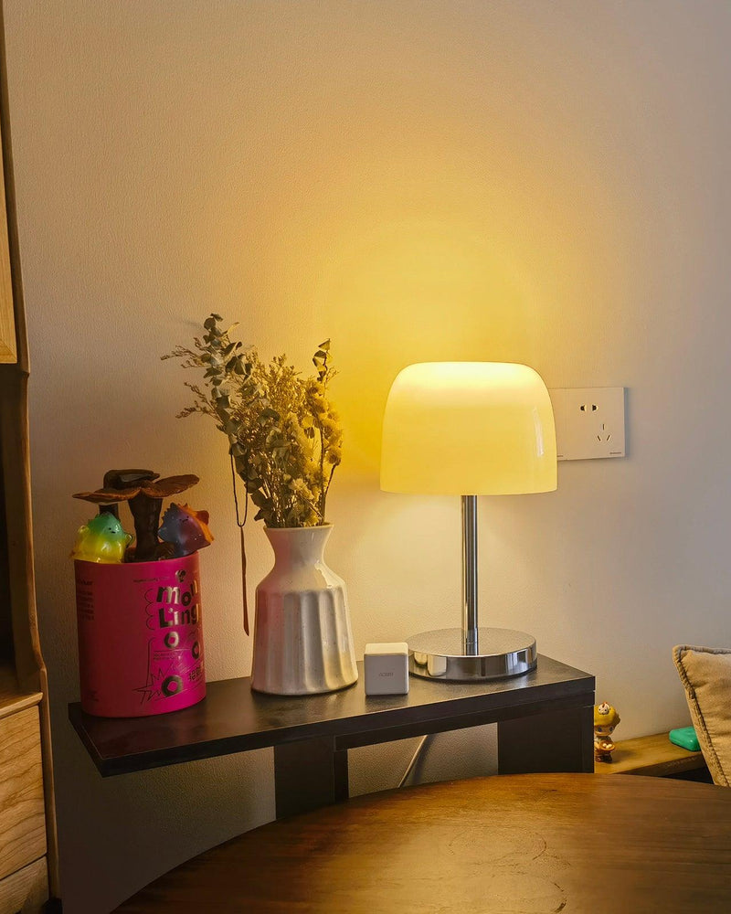 Glass table lamp VENEZIA No.01 switched on, cream shade glowing on a black shelf with vases and dried flowers