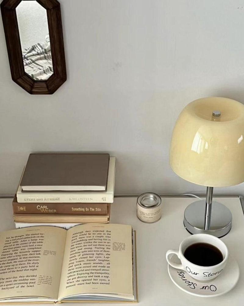 Glass table lamp VENEZIA No.01 with cream shade on a white desk with stacked books, an open book and a coffee cup