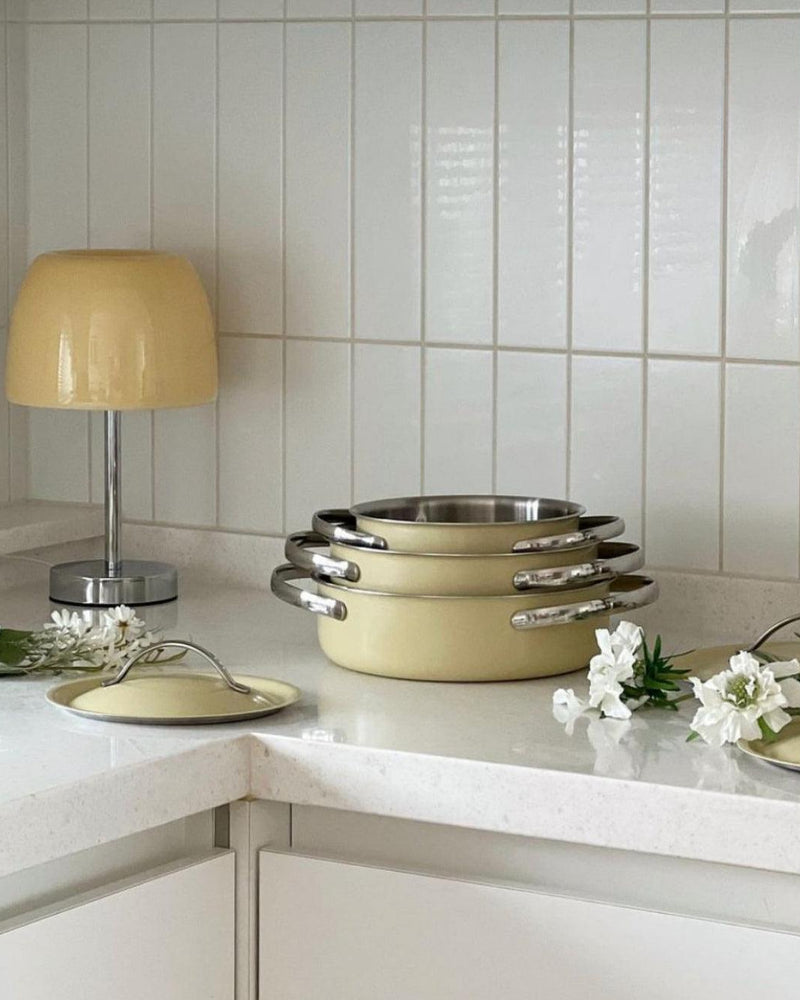 Glass table lamp VENEZIA No.01 with cream shade on a kitchen counter with a white tile wall and stacked pans