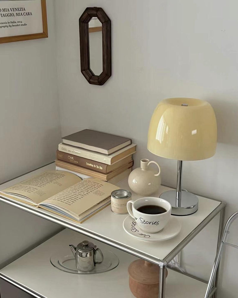 Glass table lamp VENEZIA No.01 with cream shade, unlit, on a metal shelf with books, a coffee cup and a teapot