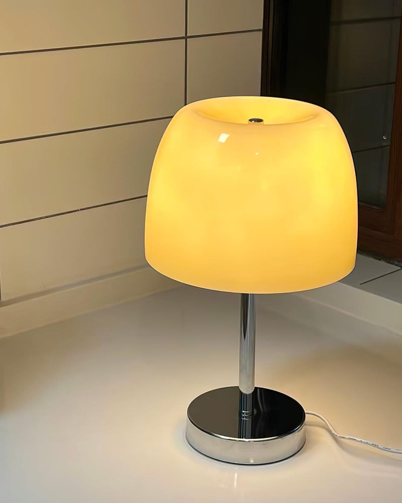 Glass table lamp VENEZIA No.01 switched on, warm yellow glow from the shade on a white table in a room corner