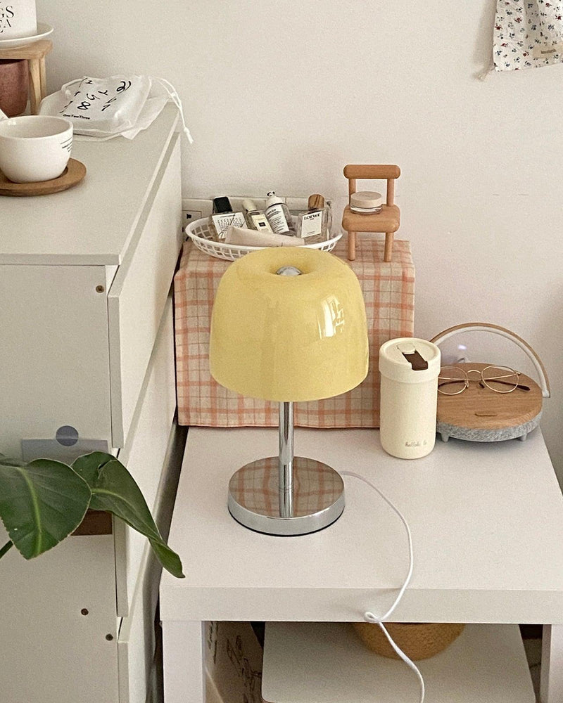 Glass table lamp VENEZIA No.01 with pale yellow shade on a white cabinet with a basket and a trailing plant