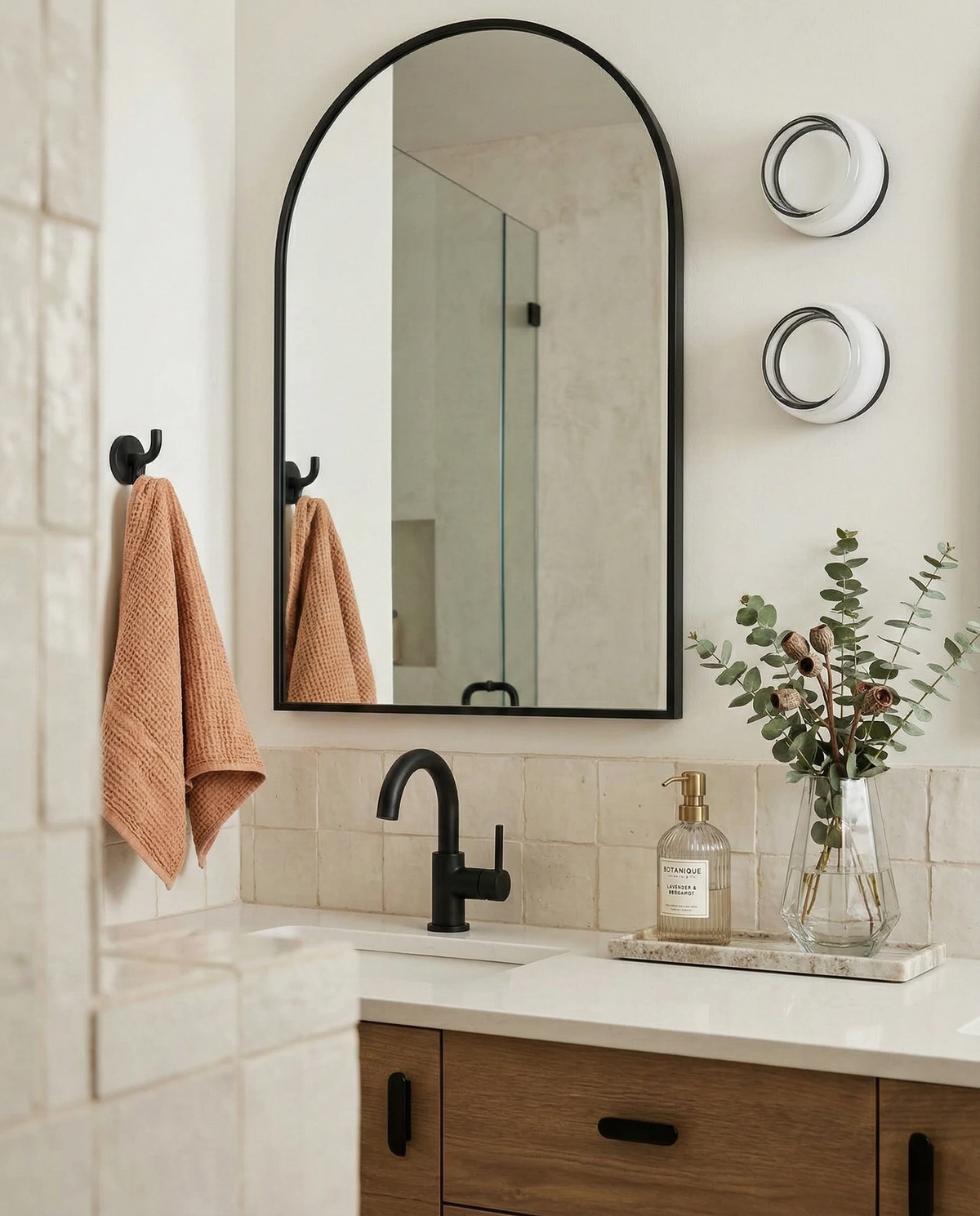 Glass wall sconce HALO No.08, two opal units next to an arched black mirror on a bathroom vanity wall