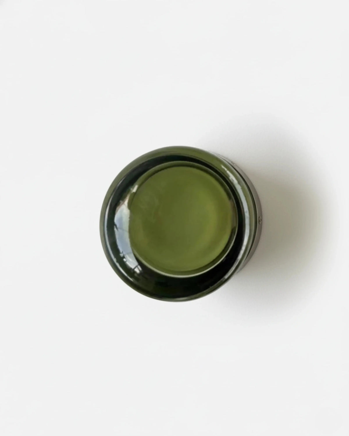 Glass wall sconce HALO No.08 in Forest Green, deep green glass disc mounted on a white wall, unlit