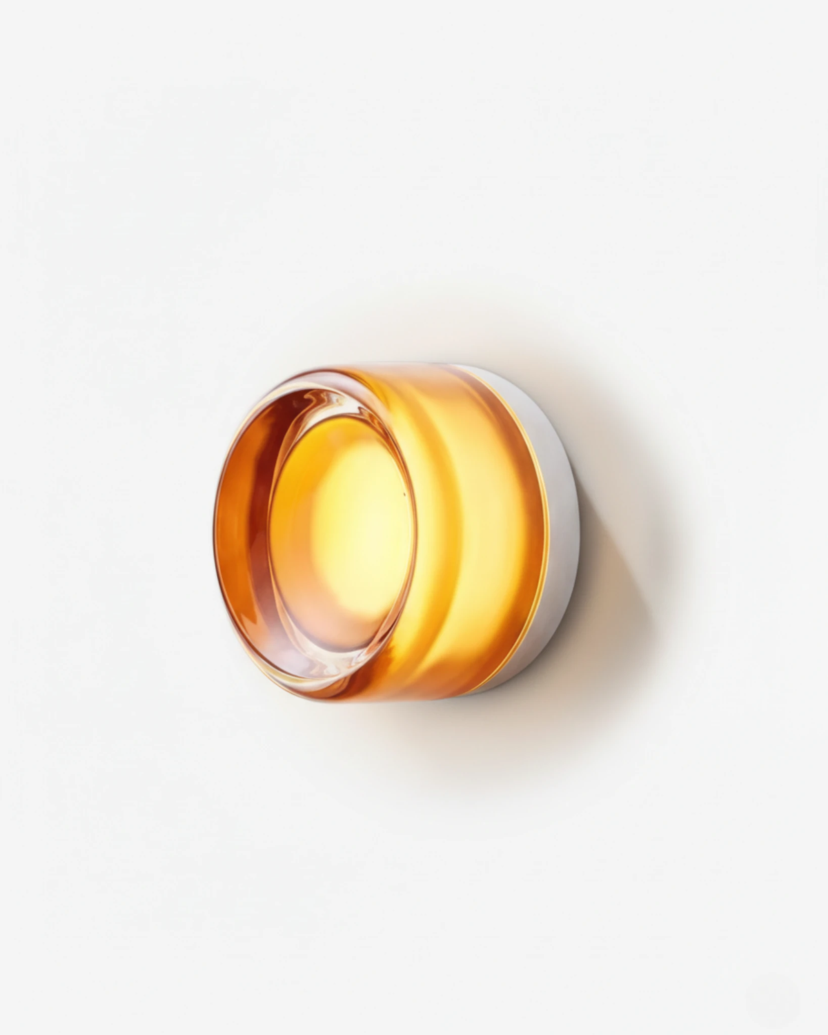 Glass wall sconce HALO No.08 in Amber, warm amber glass disc on a white base, switched on