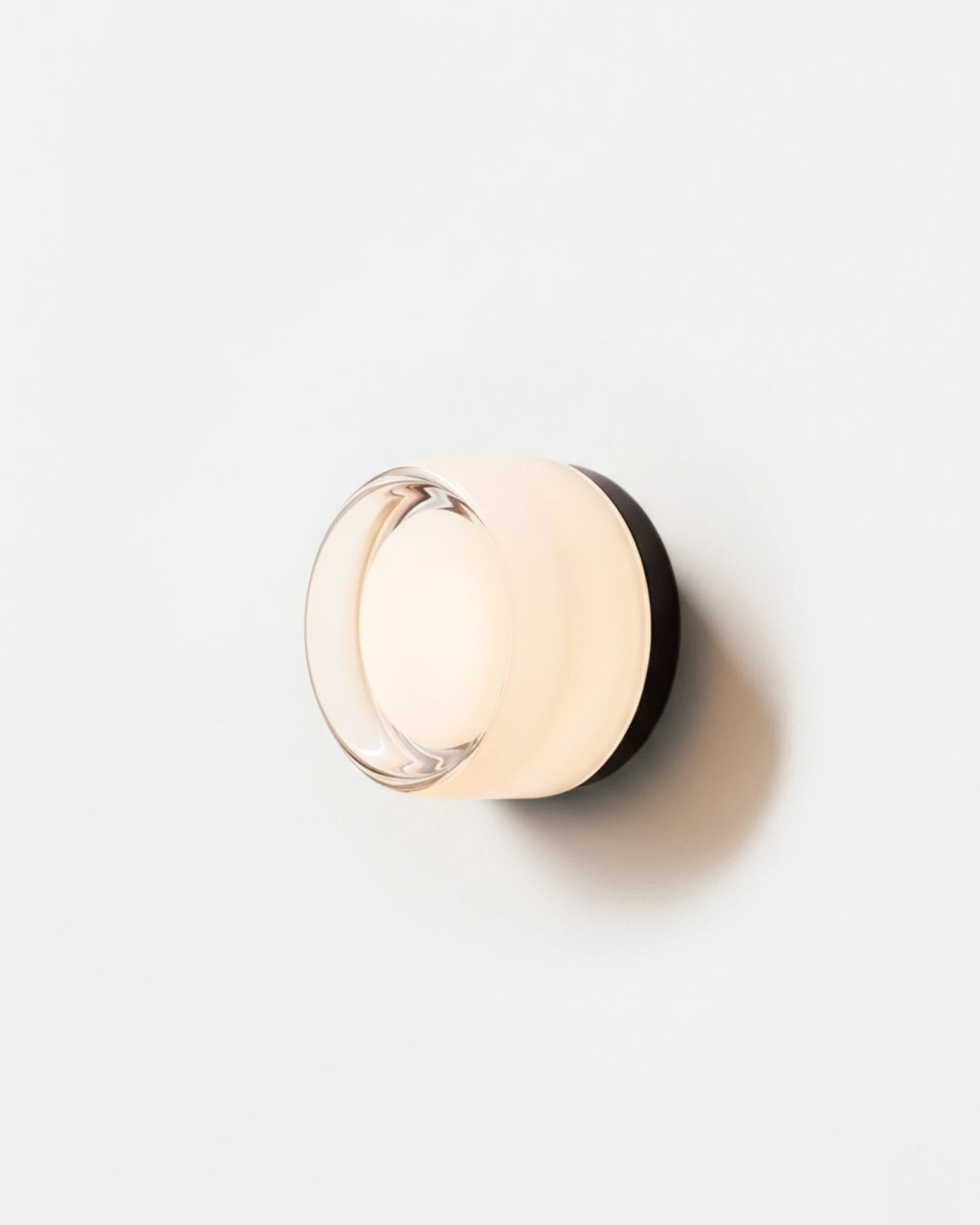 Glass wall sconce HALO No.08 in Opal, milky white glass disc on a white base, switched on