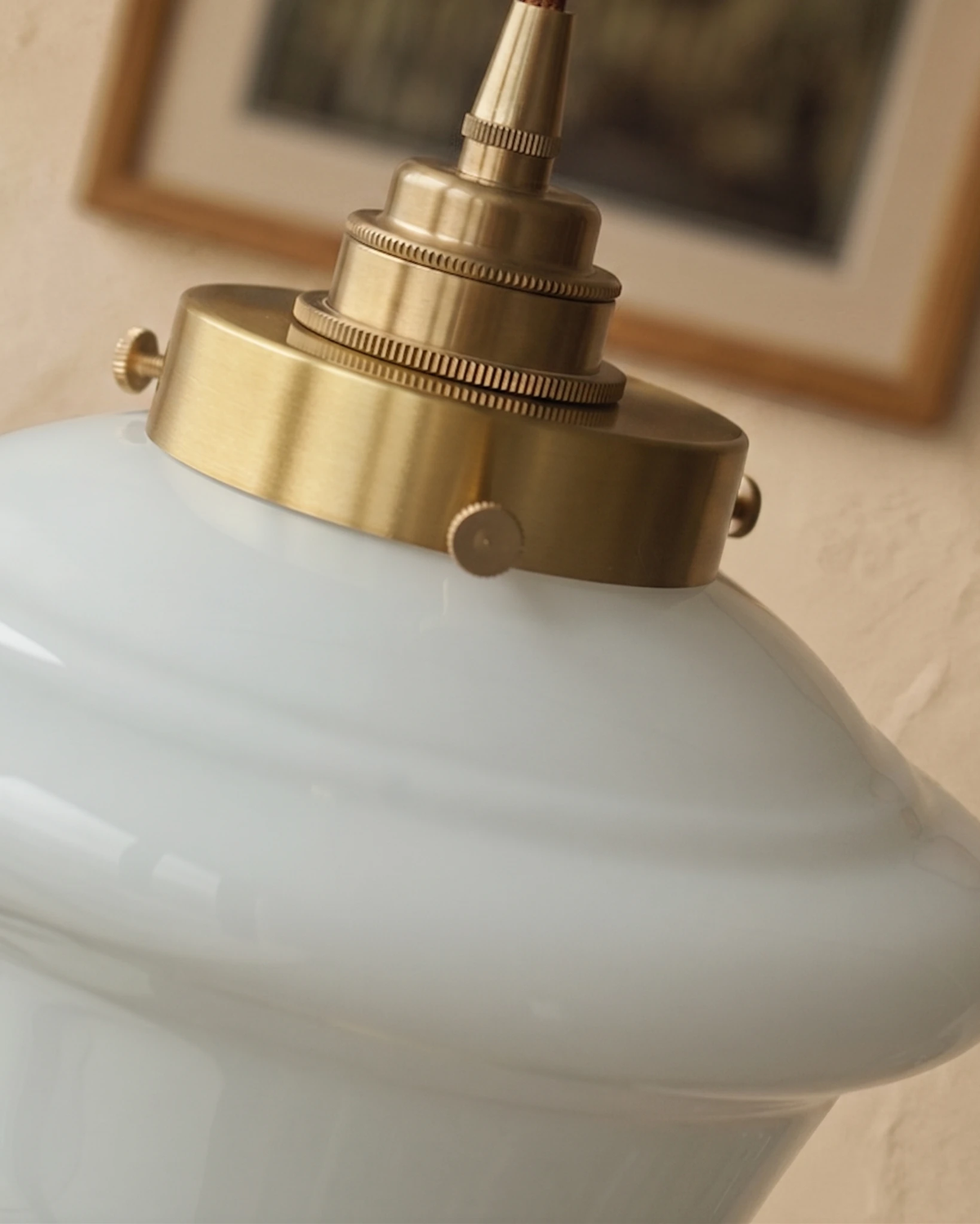 Close-up of the brass fitter and ribbed cap on the opaline glass of the SCOLA No.01 globe pendant light