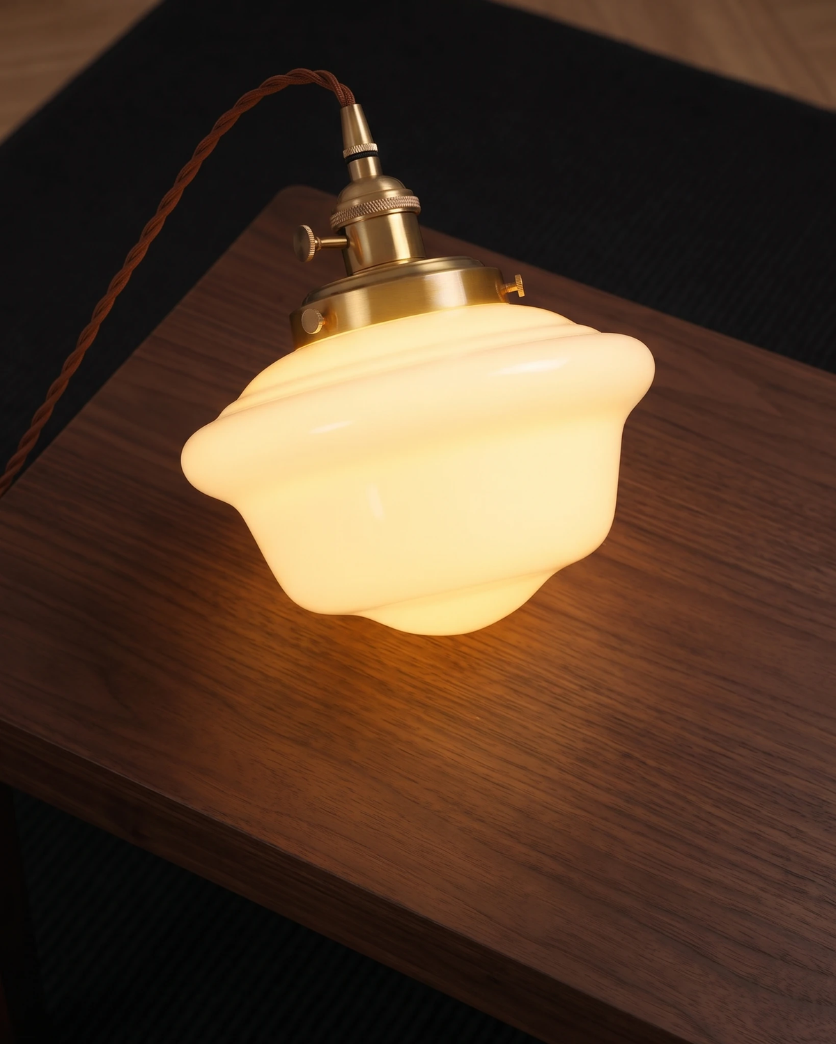 Close-up of the SCOLA No.01 globe pendant light switched on, glowing opaline shade resting on a walnut surface