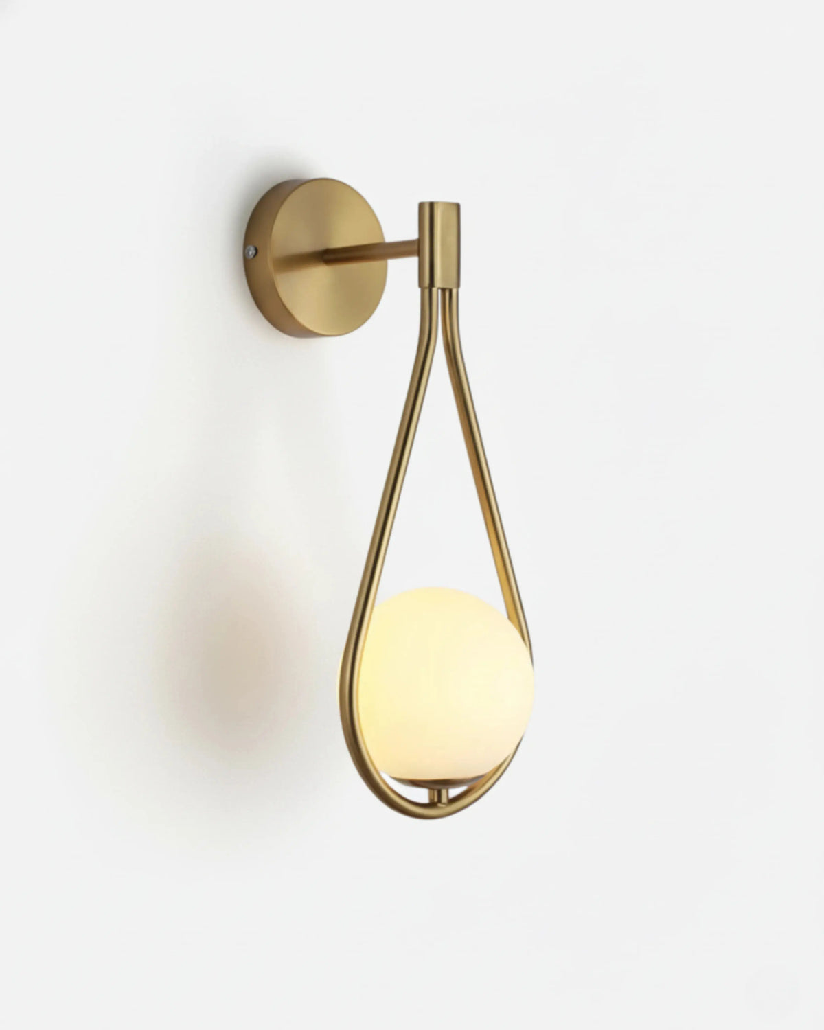 Globe wall sconce FILO No.01 in Brushed Gold, frosted opal globe glowing inside a teardrop loop bracket