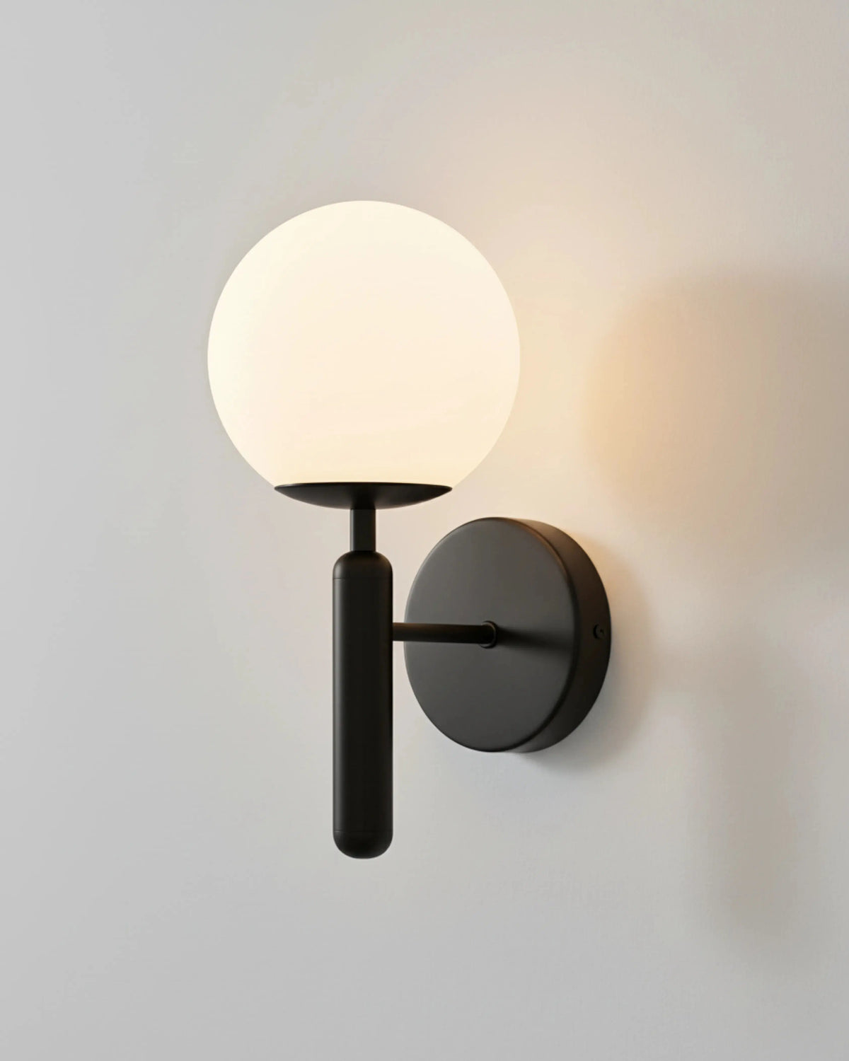 Globe wall sconce CIELO No.01 in matte black, large opal globe lit on a black arm and round backplate